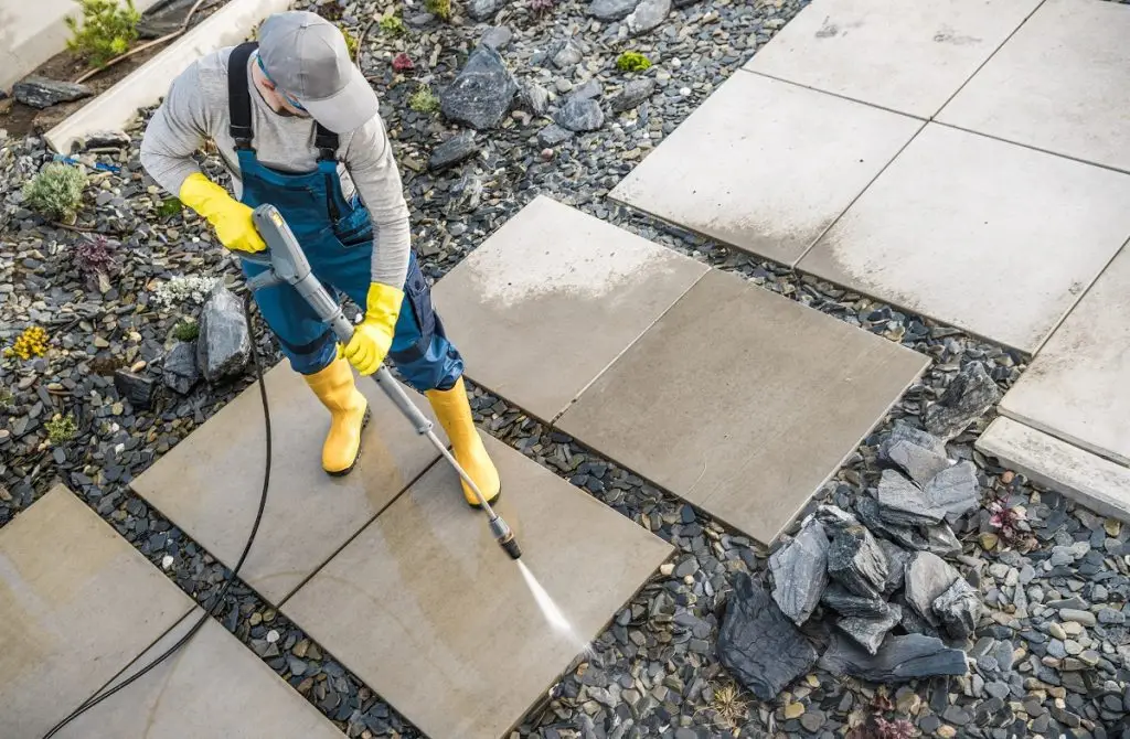 man pressure washing walkway